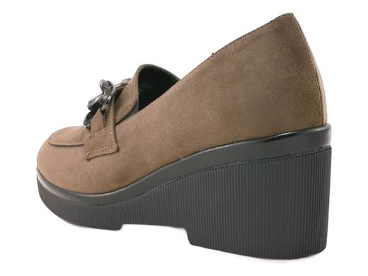Mocassini con zeppa Cinzia Soft: eleganza e comfort Made in Italy per look raffinati da mattina a sera.<br /><br />Quando la comodità incontra il buon gusto, ecco i mocassini con zeppa Cinzia Soft DM125058. Realizzati in morbido camoscio sintetico color fango, si distinguono per l’ampio accessorio a catena che dona un tocco chic e deciso.<br /><br />Gli elastici laterali rendono la calzata pratica e confortevole, mentre il sottopiede in pelle imbottito coccola ogni passo. La zeppa da 6 cm in gomma antiscivolo garantisce stabilità e slancio, senza rinunciare all’eleganza.<br /><br />Perfetti per dare un twist sofisticato ai tuoi outfit da ufficio o per le serate più ricercate. Ovviamente Made in Italy.<br /><br />Lasciati conquistare dal comfort raffinato di Cinzia Soft e aggiungili subito al carrello!